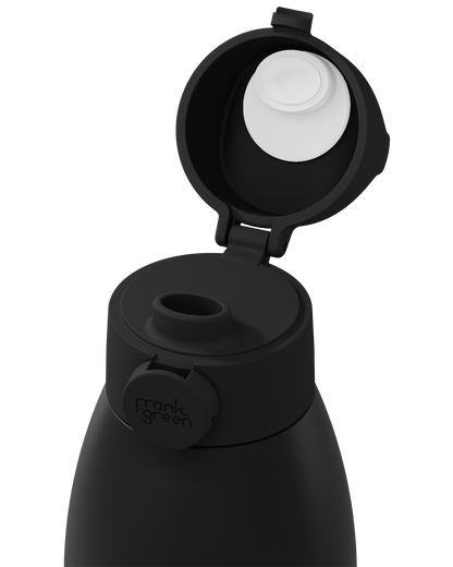 Close-up of a black frank green insulated bottle with the flip-top lid open, showing the white inner cap and the brand name on the side tab, on a white background.