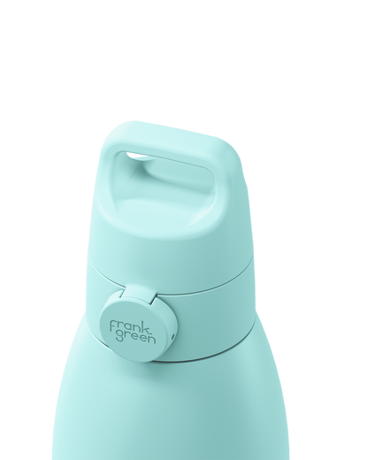 Close-up of a mint green insulated bottle with a flip-top lid and a circular frank green logo button, shown on a white background.