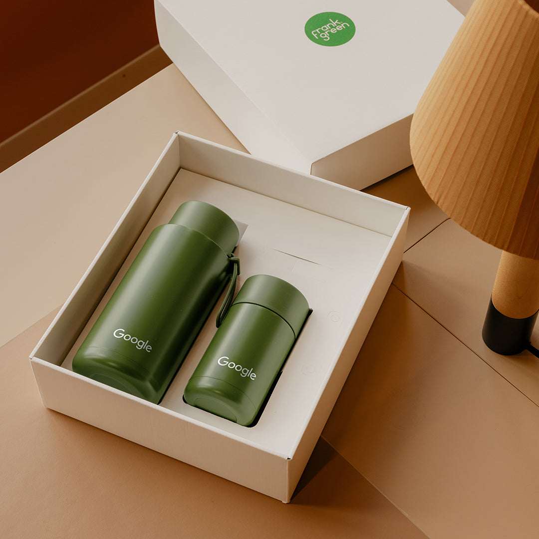 Two green Google thermos bottles in a white box on a beige surface.
